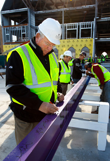 Athletics director as well as basketball coach, Steve Fritz signs the last (and a purple) beam to be hoisted into the Anderson Student Center during a topping-out ceremony. The center is under construction on the St. Paul campus. 