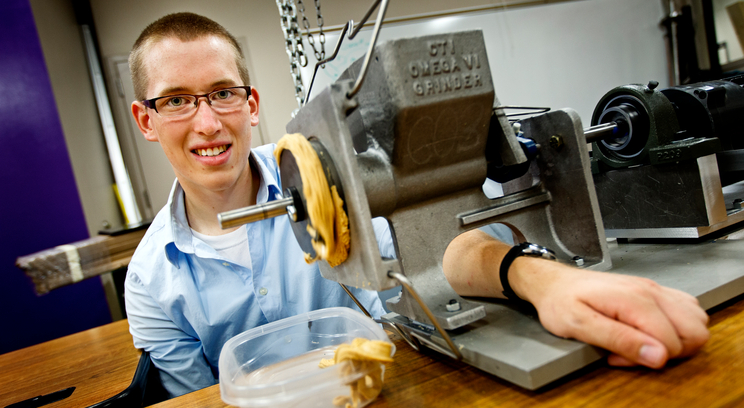 Mechanical engineering student Noel Naughton with the Omega VI peanut grinder used to make peanut butter for his and Dr. Jim Ellingson's summer research project. Photo by Mike Ekern '05.