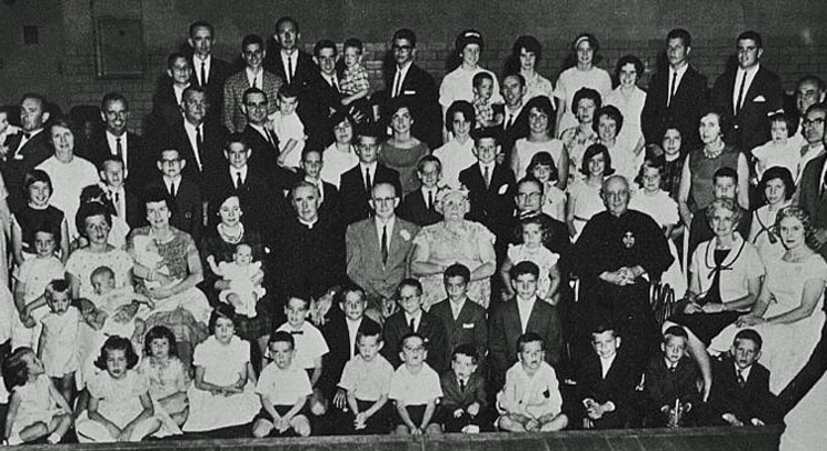Never mind about Waldo … where’s Bernard Vincent Brady? This 1963 photo of a large Irish family has three of them. The youngest Bernard Vincent Brady in the photo is familiar to the University of St. Thomas community; now chair of the university’s Theology Department, he is the boy wearing a bowtie in the second row and fifth from the left.  The woman who is holding a baby behind him is his mother, Nora (Leneghan) Brady from County Mayo, Ireland.  The priest directly behind him is his uncle, the second Bernard Vincent Brady. To the right of the priest are the bowtie boy’s grandparents, Emmet and Ethel (Kalaher) Brady, who were celebrating their golden wedding anniversary. The priest seated to the right of Emmet and Ethel is Leo Patrick Brady, C.P., and the priest to the right of Leo is the third Bernard Vincent Brady, C.P.  This clan of Bradys originally came from County Clare in Ireland. The family photo was taken at a parish hall in Akron, Ohio.