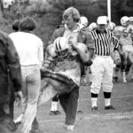 Offensive line coach Mark Dienhart assists a player off the field at St. John's in 1977.