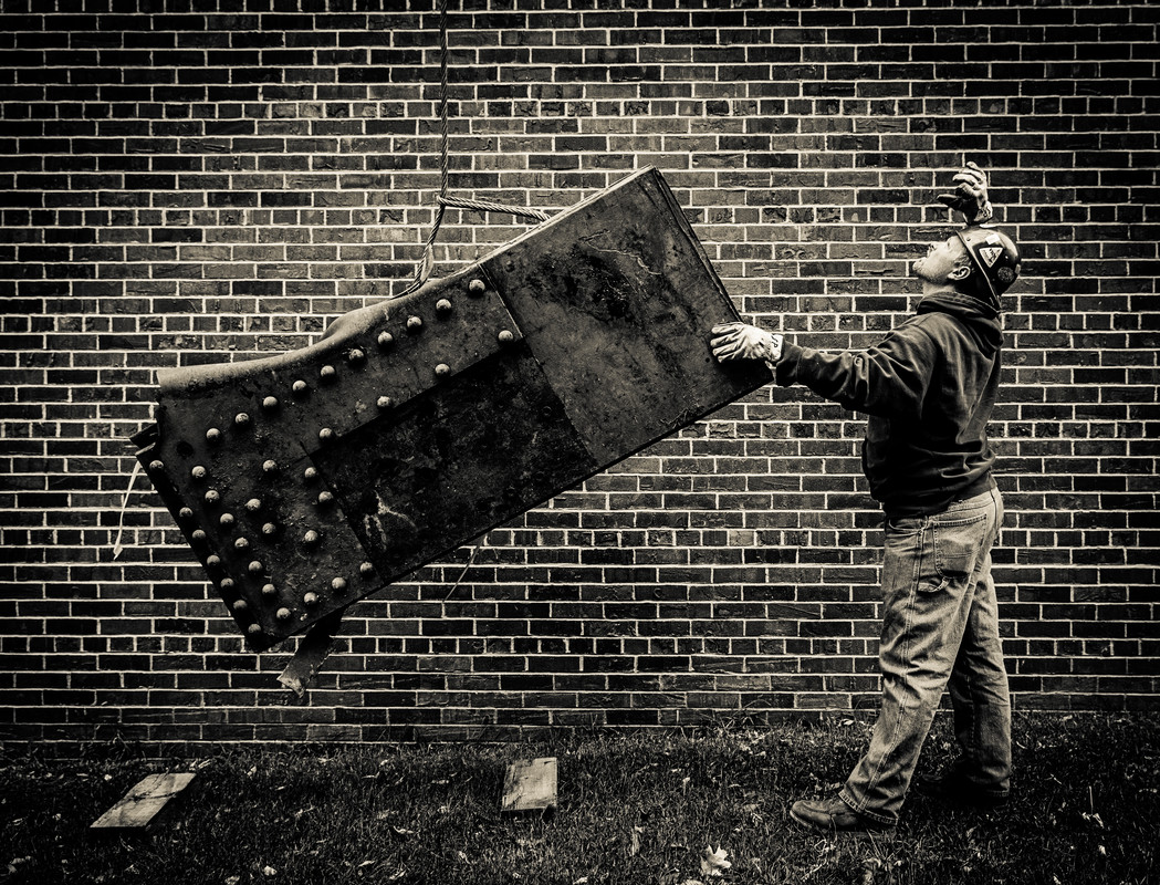 A worker lowers a piece of 35W bridge debris into its temporary holding location behind Brady Education Center. School of Engineering dean Don Weinkauf secured three pieces of the fallen 35W bridge for St. Thomas. They will eventually be displayed near the Frey Science and Engineering Center where they will be involved in a ceremony for graduating engineering students. (Photo by Mike Ekern '02)