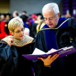 President Julie Sullivan, and president emeritus Fr. Dennis Dease look over their script in Schoenecker Arena  prior to the ceremony. (Photo by Mike Ekern '02)