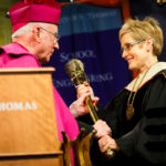 Archbishop Emeritus and trustee Harry Flynn hands the presidential mace to President Julie Sullivan. (Photo by Mark Brown)