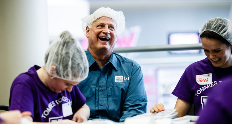 Feed My Starving Children executive director and alum Mark Crea '78 laughs with volunteers during the St. Thomas Day of Service mobile pack event May 6, 2015 in the Anderson Student Center's Campus Way. Feed My Starving Children brought mobile supplies to St. Thomas where faculty, staff and student volunteers packed thousands of meals for children without food overseas.