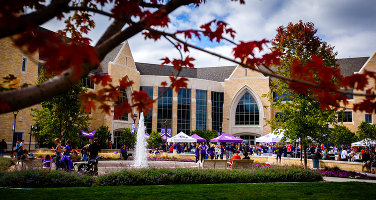Fans fill the John P. Monahan Plaza for Purple on the Plaza before the Tommie Johnnie football game September 21, 2013. The Anderson Student Center is in the background and fall leaves on a tree are in the foreground. St. Thomas would lose to Saint John's 18-20.