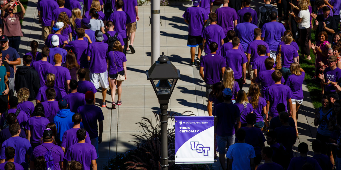 Incoming freshmen walk across the lower quad past clapping faculty and staff during the freshman March Through the Arches September 2, 2014. A "Think Critically" mission sign is prominently featured.