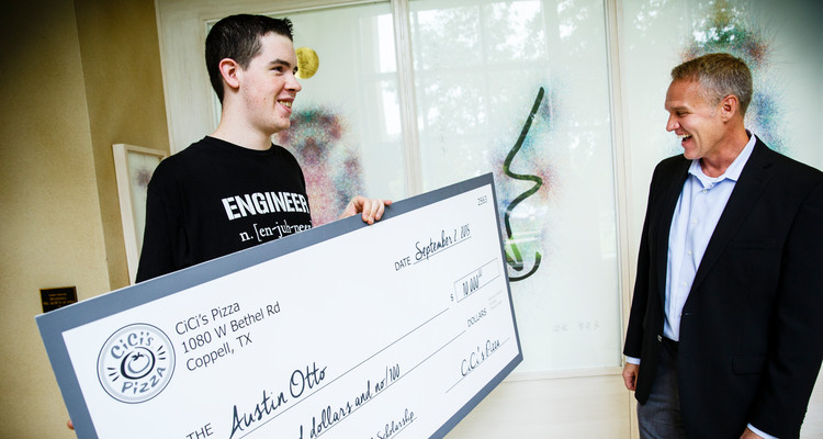 Austin Otto (Mechanical Engineering) holds a $10,000 check with CiCi's Pizza CEO Darin Harris, right, on September 2, 2015 in the Owens Science Hall in St. Paul. Austin Otto won $10,000.00 through the CiCi's Pizza Photo Scholarship Contest. Otto wrote an essay and snapped a picture of himself in a CiCi's Pizza restaurant. He initially thought he was being interviewed about his 3D Printing engineering research and was surprised by his parents with the check after CiCi's CEO Darin Harris announced that he had won the scholarship.