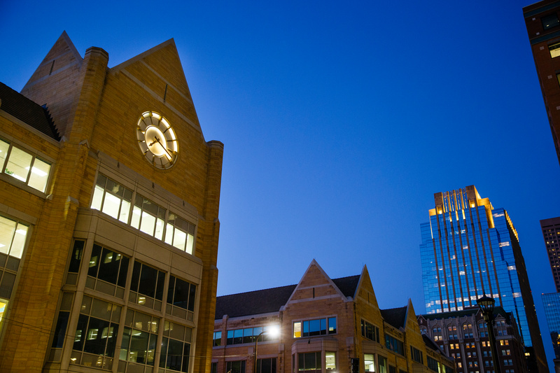 The glowing clock tower of Terrence Murphy Hall is seen against the Minneapolis skyline the night of October 5, 2015.