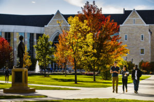 Students walk along the lower quad October 14, 2015 amidst trees in autumn color. The Anderson Student Center is in the background and the statue of John Ireland is at left.