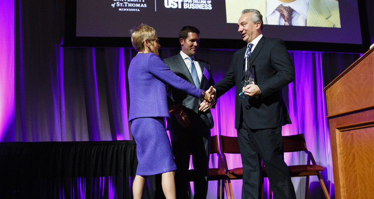 Luigi Bernardi ('85, MBA) receives the John F. Cade Award for outstanding achievement as an entrepreneur from UST President Dr. Julie Sullivan during the 2015 Entrepreneurship Awards gala in the Schulze Grand Atrium in the School of Law building in downtown Minneapolis on November 19, 2015. Bernardi is president of Aurora Investments LLC, a real estate firm based in Edina. Standing in the background is Michael L. Reger ('00 MBA) president and CEO of Norther Oil & Gas, Inc, and 2014 recipient of the John F. Cade Award.