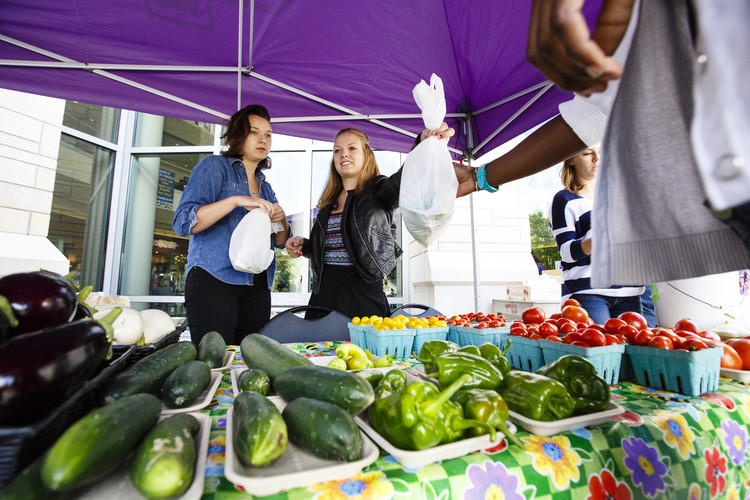 Student volunteers Marnie Sciamanda (Biology) and Ashley Brundrett (Biology) sell produce at the St. Thomas Farmers Market.