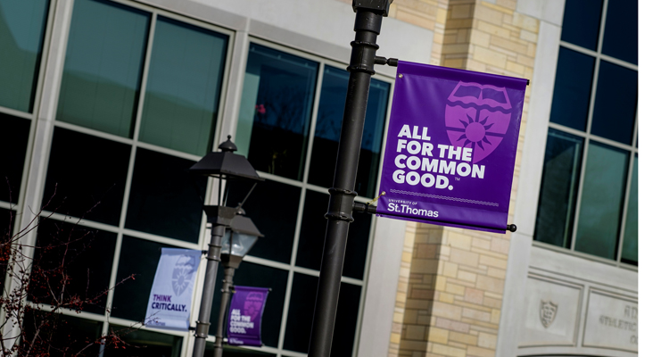 A sign reading "All for the Common Good" hangs from a lamp post on the John P. Monahan Plaza January 29, 2016. The Anderson Athletic and Recreation Complex is in the background.
