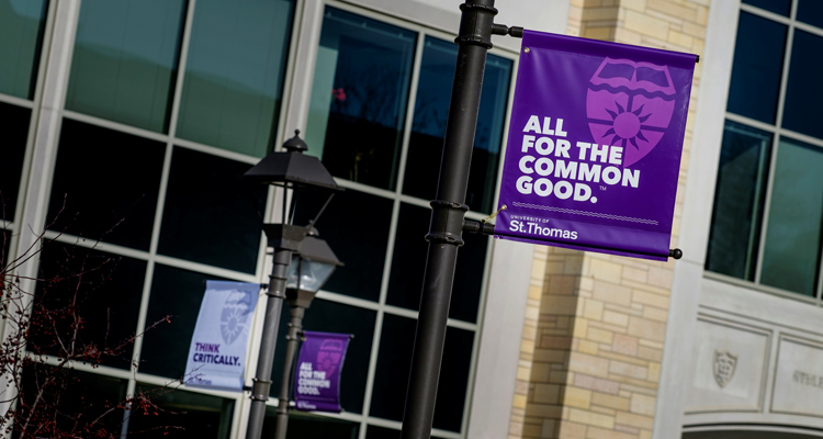 A sign reading "All for the Common Good" hangs from a lamp post on the John P. Monahan Plaza January 29, 2016. The Anderson Athletic and Recreation Complex is in the background.