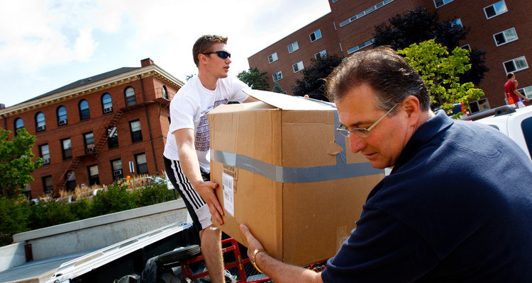 A member of "Father Dease's Moving Crew" (left) helps a parent pull a box out of a truck during move-in day September 3, 2011.