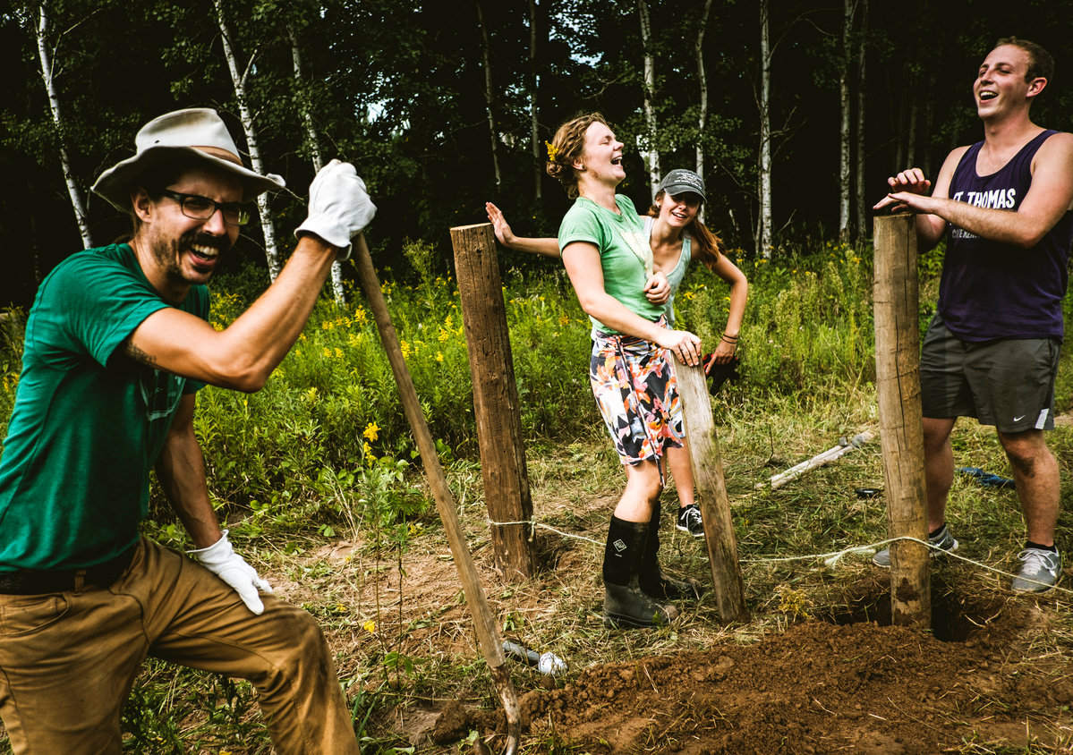 Jake Kulju '04, Meredith Heneghan '16, Natalie Thoresen and Aaron Pietrowski laugh as they build a fence on Kulju's farm.