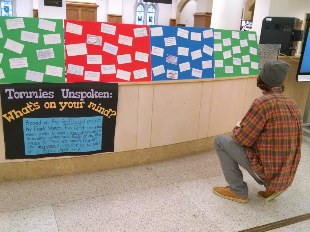 Student Riley Hare examines the comments on the Tommies Unspoken display.