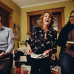 The first book discussion group was held in professor Julie Oseid's home. Here, she shares a laugh with her discussion co-leader, Kay Bolanos, a first-year student, while Scott Fulks, another student discussion leader looks on.