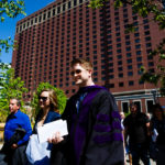 A new School of Law graduate (right) walks away from the Minneapolis Hilton following the School of Law Commencement ceremony May 13, 2017.
