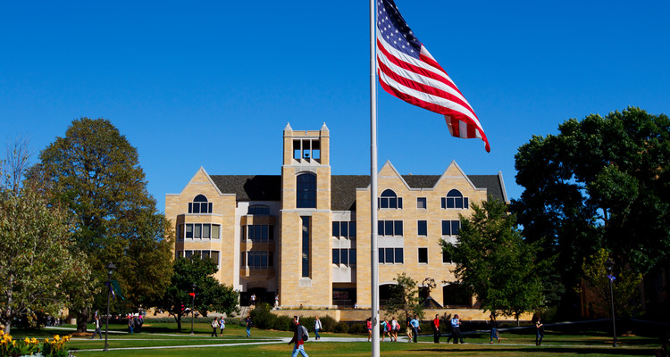 Students fill the lower quad as O'Shaughnessy-Frey Library looms in the background September 13, 2012. The American flag, at half staff, is in the foreground.