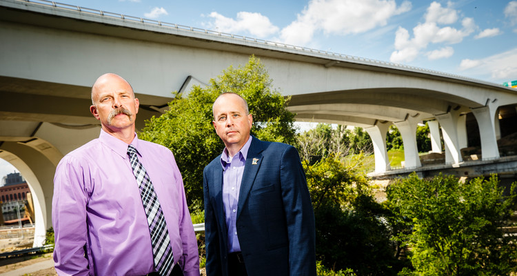 Wayne Johnson, left, and Mike Barrett, right, pose for a portrait in front of the new Interstate 35W Bridge over the Mississippi River near downtown Minneapolis on July 28, 2017. Both men worked on recovery effort 10 years ago when the original bridge collapsed on August 1, 2007. Johnson is Minneapolis manage of Public Safety and Mike Barrett is Associate Director of Public Safety and Manager of Investigations.