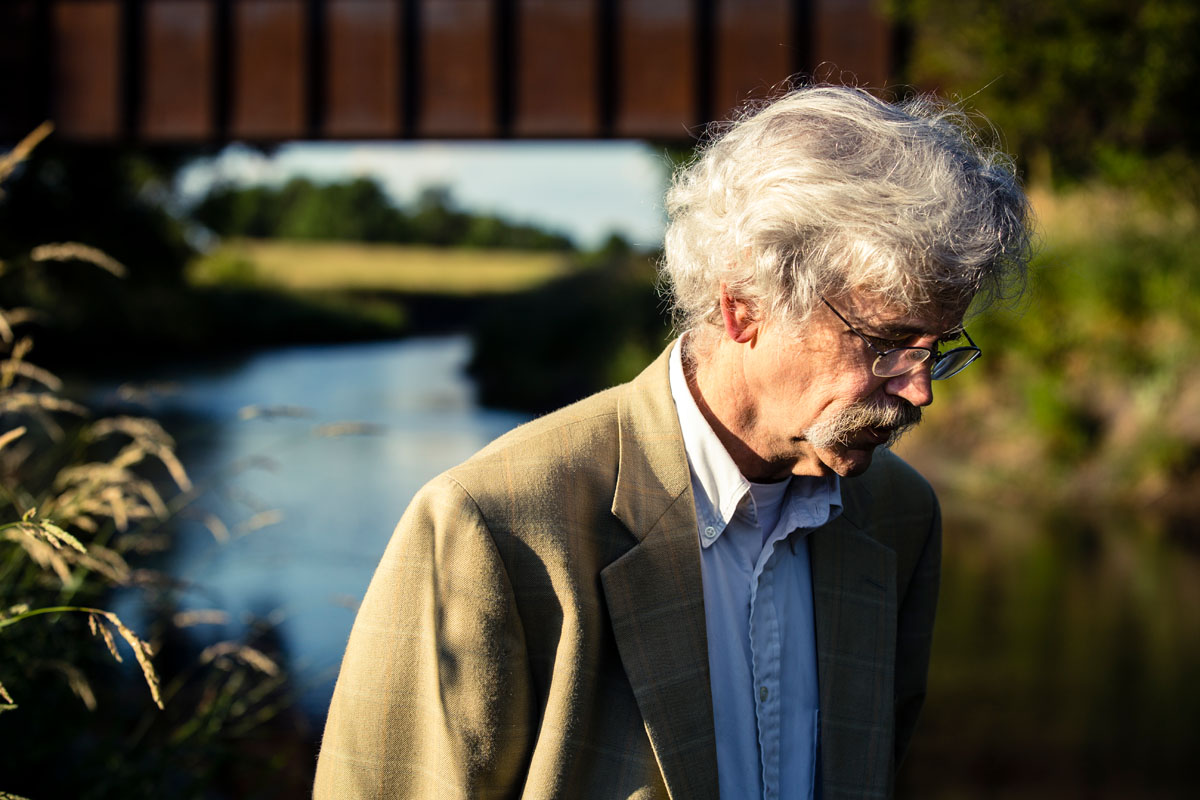 Art Cullen '80 stands next to the Raccoon River outside of Storm Lake, Iowa. Cullen was awarded a 2017 Pulitzer Prize for Editorial Writing for a series of editorials about a corporate agriculture lawsuit in Buena Vista County.