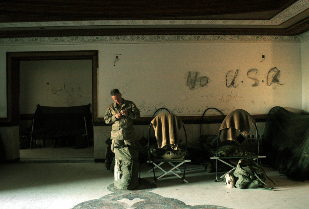 A soldier with the United States 101st Airbourne Division stands in front of Anti-American slogans drawn on the wall of the Division Main Headquarters in one of Saddam Hussain's former palaces in Mosel, Northern Iraq, May 1, 2003. The palace was Hussain's Northernmost palace in Iraq, and was his VIP palace, and now runs the entire northwest region of Iraq for the 101st Airbourne. (Credit: Lynsey Addario/ Corbis Saba)
