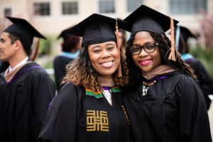 Jules Porter and a fellow student pose for a picture during the 2018 Graduate Commencement ceremony in O'Shaughnessy Stadium on May 18, 2018 in St. Paul.