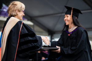 A student shakes hands with President Julie Sullivan as she receives her degree during the 2018 Graduate Commencement ceremony in O'Shaughnessy Stadium on May 18, 2018 in St. Paul.