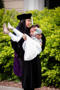 A graduate lifts a smiling child after the 2018 Graduate Commencement ceremony on the St. Paul campus on May 18, 2018 in St. Paul.