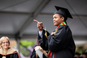 A graduating senior points at friends in the crowd as he crosses the stage to receive his diploma during the 2018 Undergraduate Commencement ceremony in O'Shaughnessy Stadium on May 18, 2018 in St. Paul.