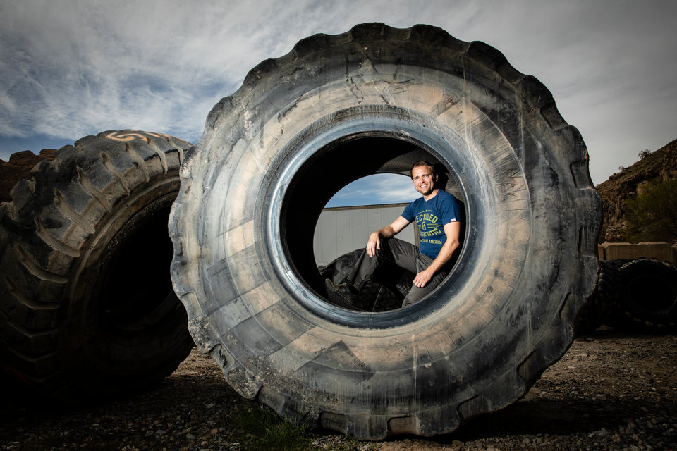 Jason Utgaard poses for a portrait in a large tire at a rubber recycling facility in Salt Lake City, Utah, on April 19, 2018. Jason Utgaard, '07 Entrepreneurship, founded The Spotted Door, an online retailer that sells recycled and reclaimed products.