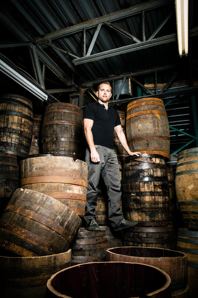 Jason Utgaard stands on old whiskey barrels at BarHomeDesigns in Salt Lake City, Utah. Jason Utgaard, '07 Entrepreneurship, founded The Spotted Door, an online retailer that sells recycled and reclaimed products. BarHomeDesign supplies The Spotted Door with furniture made from repurposed whiskey Barrels.