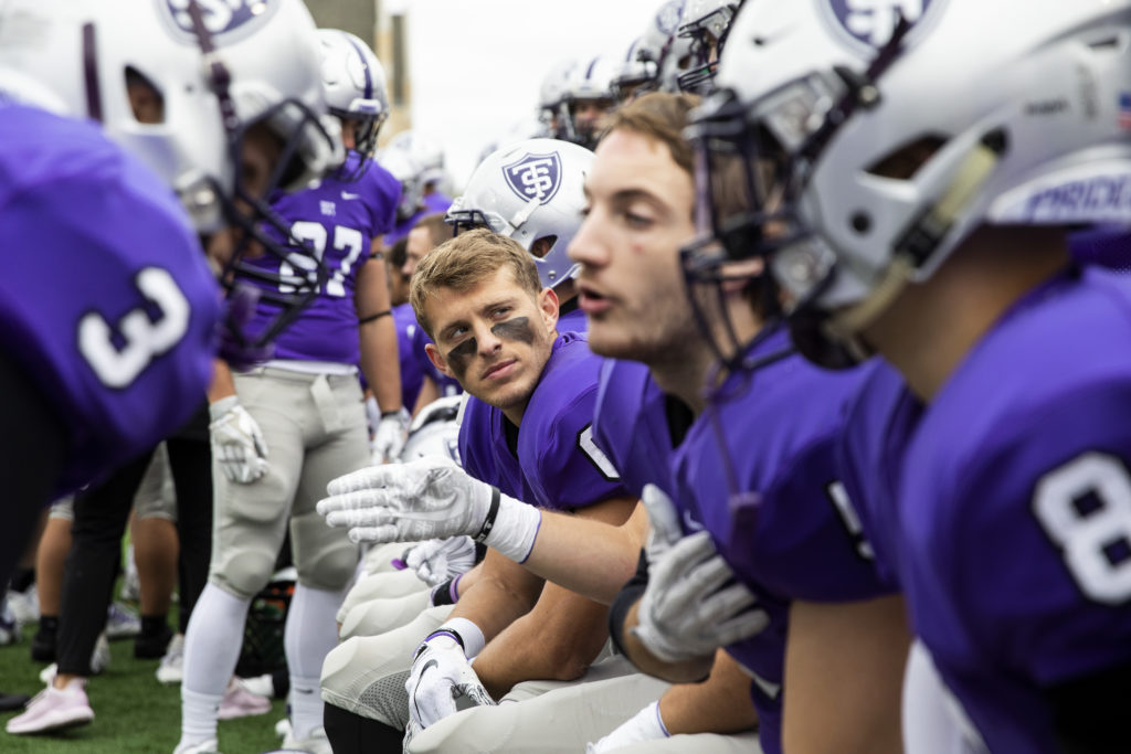 St. Thomas football players talk on the bench during the Homecoming game against Augsburg College.