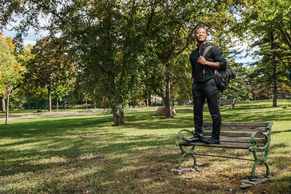 Environmental portrait of student Victor Sikeley at a bench on Summit Avenue in St. Paul. Sikeley, originally from Ghana, works through his organization "Initiative for a Better Africa" to improve education in Africa.