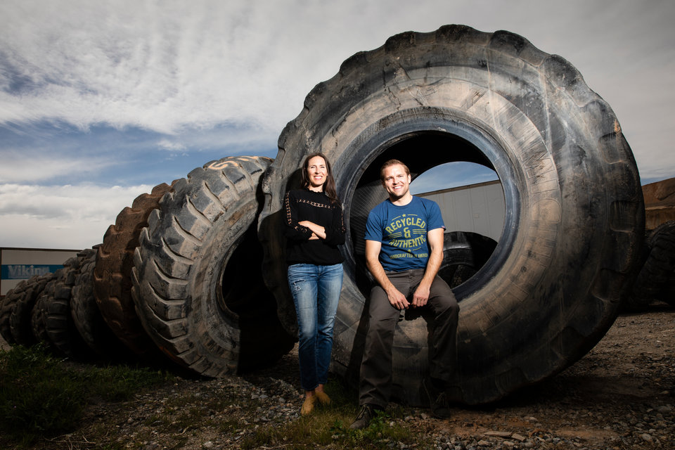 Amy Keele of TUB People, left, poses for a portrait with Jason Utgaard, right, next to large tires at a recycling facility in Salt Lake City, Utah, on April 19, 2018. Jason Utgaard, '07 Entrepreneurship, founded The Spotted Door, an online retailer that sells recycled and reclaimed products. Keele's company makes wallets and other products from recycled inner tubes. Utgaard sells the products on his site.