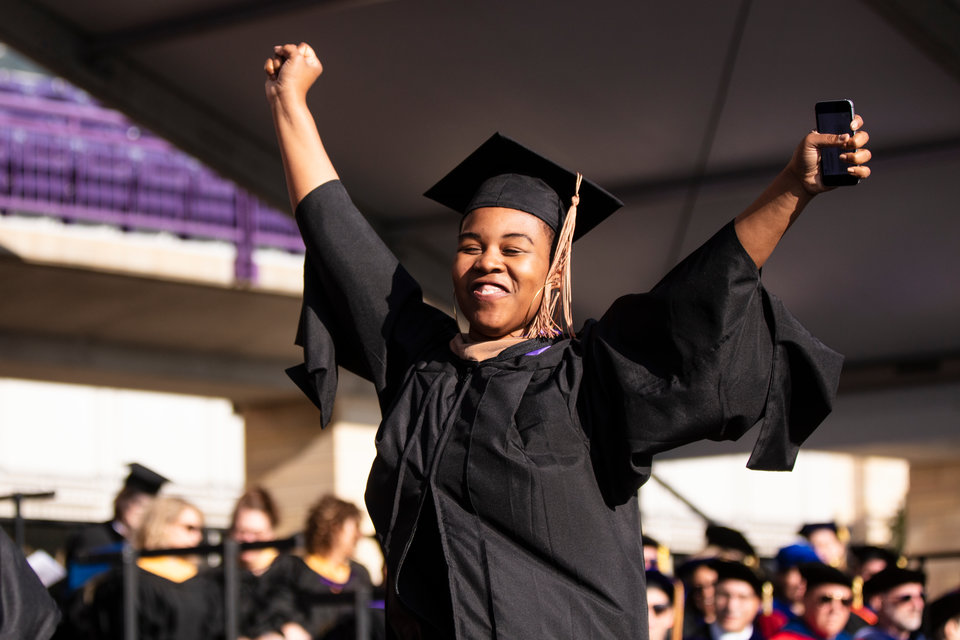A student raises her arms in celebration as she walks across stage during the 2019 Graduate Commencement Ceremony in O’Shaughnessy Stadium on May 25, 2019 in St. Paul.