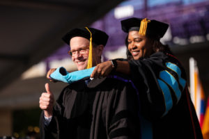 A student gives a thumbs up while being hooded by School of Education Dean Dr. Kathlene Holmes Campbell during the 2019 Graduate Commencement Ceremony in O’Shaughnessy Stadium on May 25, 2019 in St. Paul.