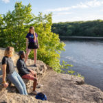Students Sarah Benoy, Shukrani Nangwala and Mackenzie Stahl talk on the river bluffs overlooking the Mississippi River.