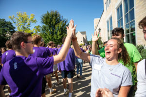A student gets a high five during the annual March through the Arches to celebrate the start of the school year and the arrival of a new class of freshmen on campus on September 3, 2019, in St. Paul.