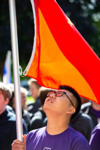 An international student looks up at his flag during the annual March through the Arches to celebrate the start of the school year and the arrival of a new class of freshmen on campus on September 3, 2019, in St. Paul.