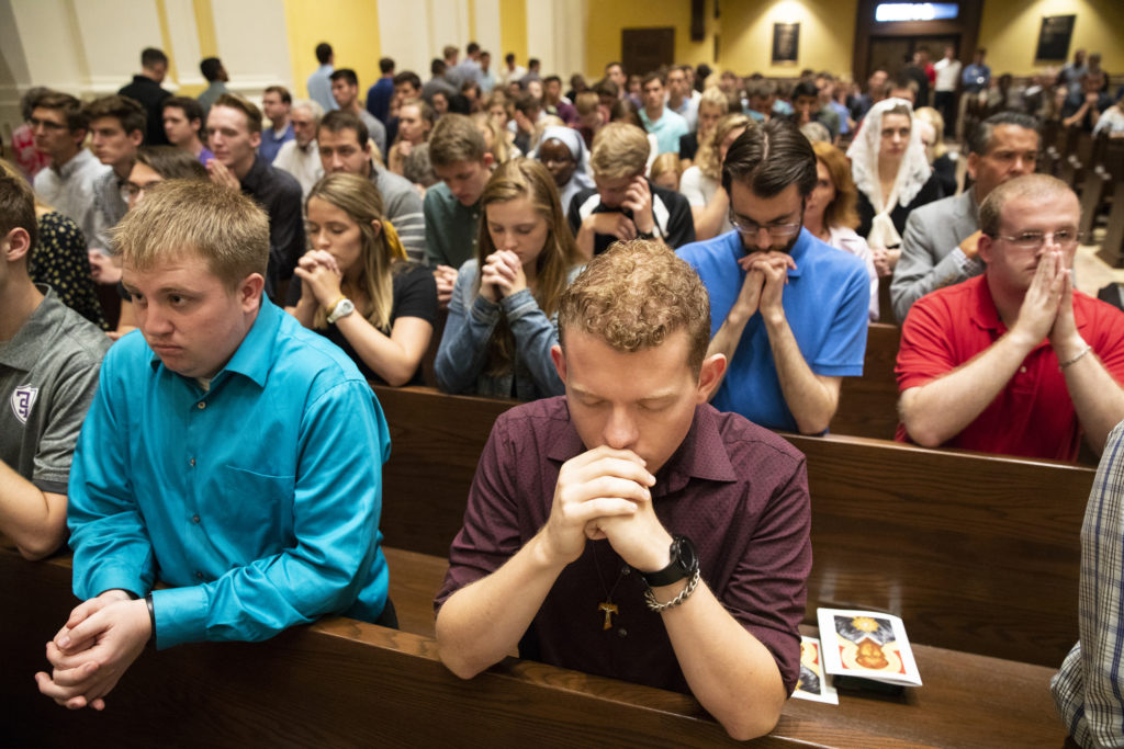 Students fold their hands in prayer during the Opening Mass Sept. 5, 2019 in the newly renovated interior of the Chapel of St. Thomas Aquinas.