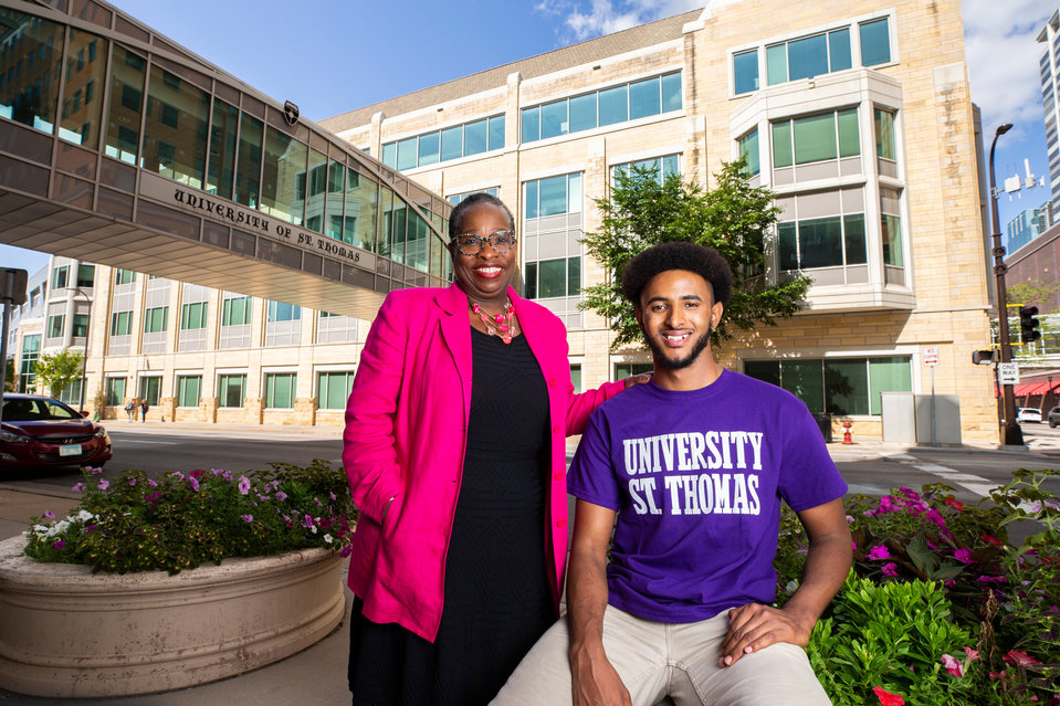 Dougherty Family College student Tamu Lajebo, right, and his mentor professor Aura Wharton-Beck pose together for a portrait outside of Opus Hall on the Minneapolis campus.