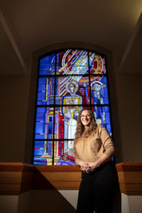 Art History and Catholic Studies major Hannah Rose Shogren Smith poses for a portrait in the O’Shaughnessy-Frey Library in front of the St. Thomas Aquinas window. Mark Brown/University of St. Thomas