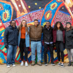College of Arts and Sciences faculty and students participating in the SOLV initiative stand in front of the Braided, a mural that is part of the Midway Murals project, in St. Paul. Mark Brown/University of St. Thomas