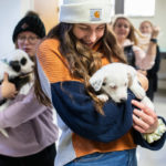Students hold puppies after making a donation to help celebrate and promote Tommie Give Day. Liam Doyle/University of St. Thomas