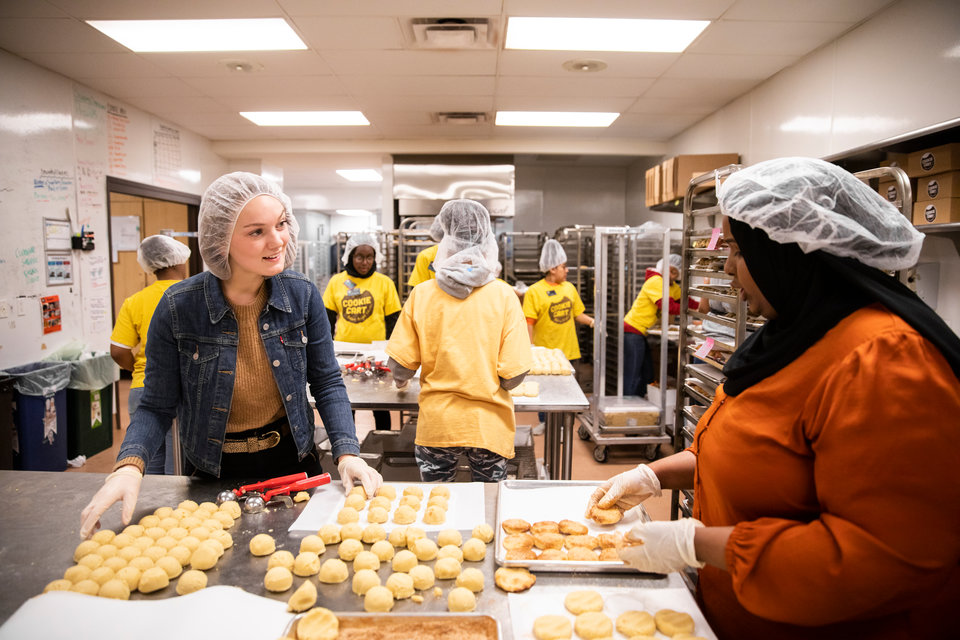 St. Thomas seniors Maddy Morehouse, left, and Sarah Isse, right, work alongside teen youth, volunteering at Cookie Cart, a bakery and non-profit that employs teenagers, providing them with leadership skills and work experience, in Minneapolis on December 19, 2019.