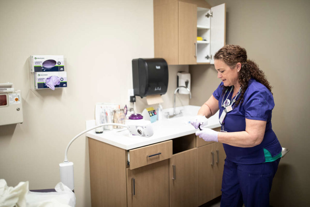 Registered Nurse Katy Steigauf disinfects an exam room at the Center for Well-Being. Critical staff remain on campus to serve a small number of students still residing in on-campus housing. Mark Brown/University of St. Thomas