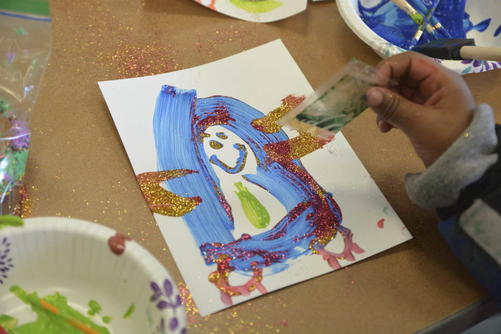 A child at Catholic Charities works on a project with St. Thomas students.