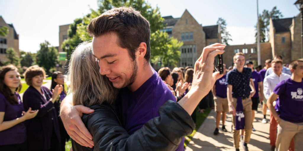 A student hugs his mother during the annual March through the Arches to celebrate the start of the school year and the arrival of a new class of freshmen on campus on September 3, 2019, in St. Paul.