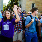 A student waves to the Facebook live camera during the March Through the Arches event September 8, 2016.